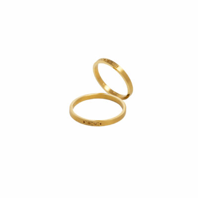 Gold Wedding Bands – Elsa Mouzaki Two gold wedding bands with geometric details on a white background.