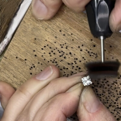 Hand-polishing the bespoke white gold diamond pendant with a rotary tool at the jeweller’s bench.
